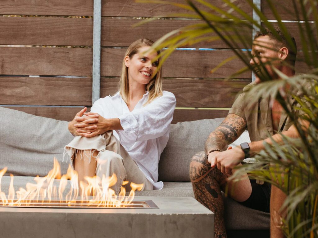 a couple sitting beside a modern fire pit 