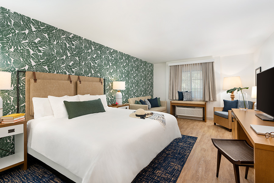 Hotel guest room with tropical foliage wallpaper at Mason Beach Inn