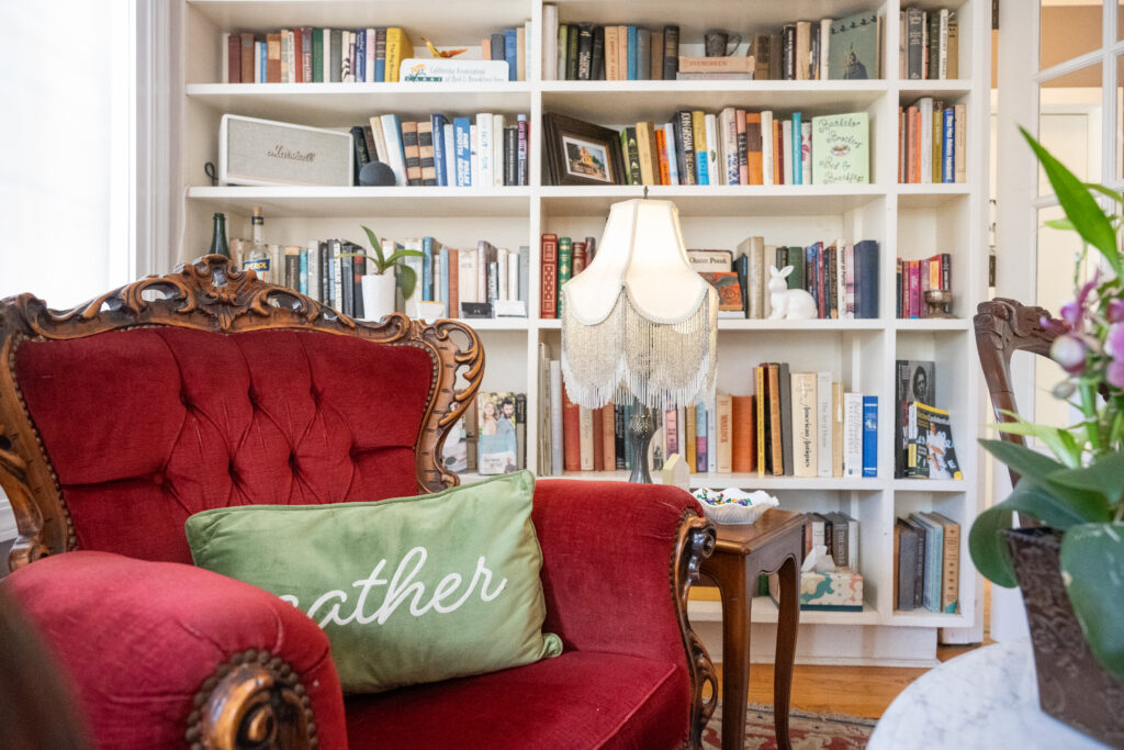 Library with bookcases full of books and an antique red velvet chair and side table