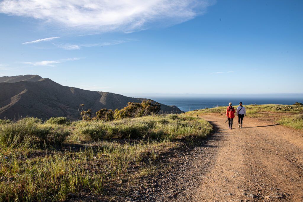 Two hikers on Catalina Island with ocean views in the background