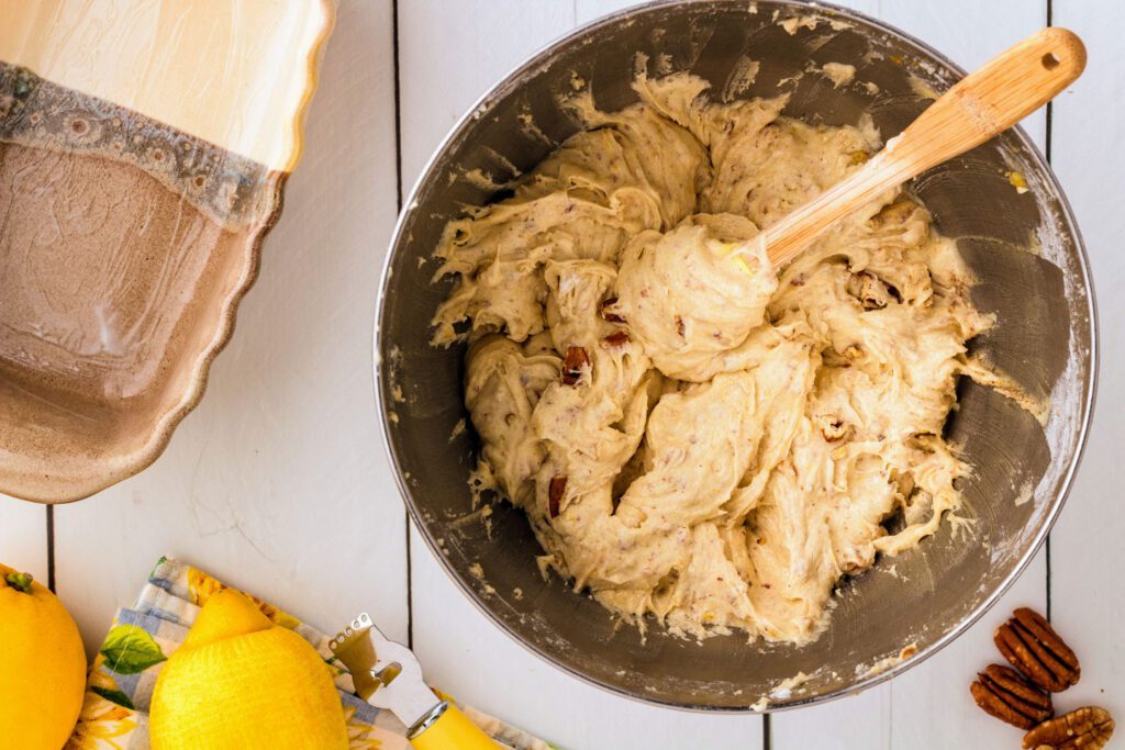Mixing the lemon zest and chopped nuts into the batter.