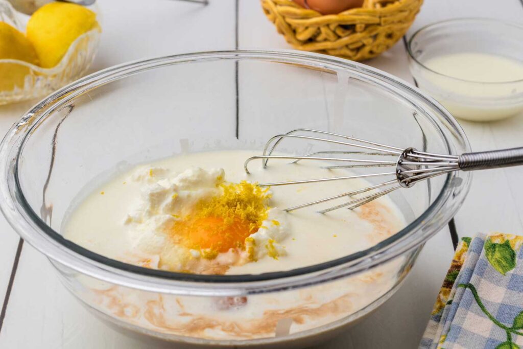 Wet ingredients for the pancake batter in a mixing bowl with a whisk