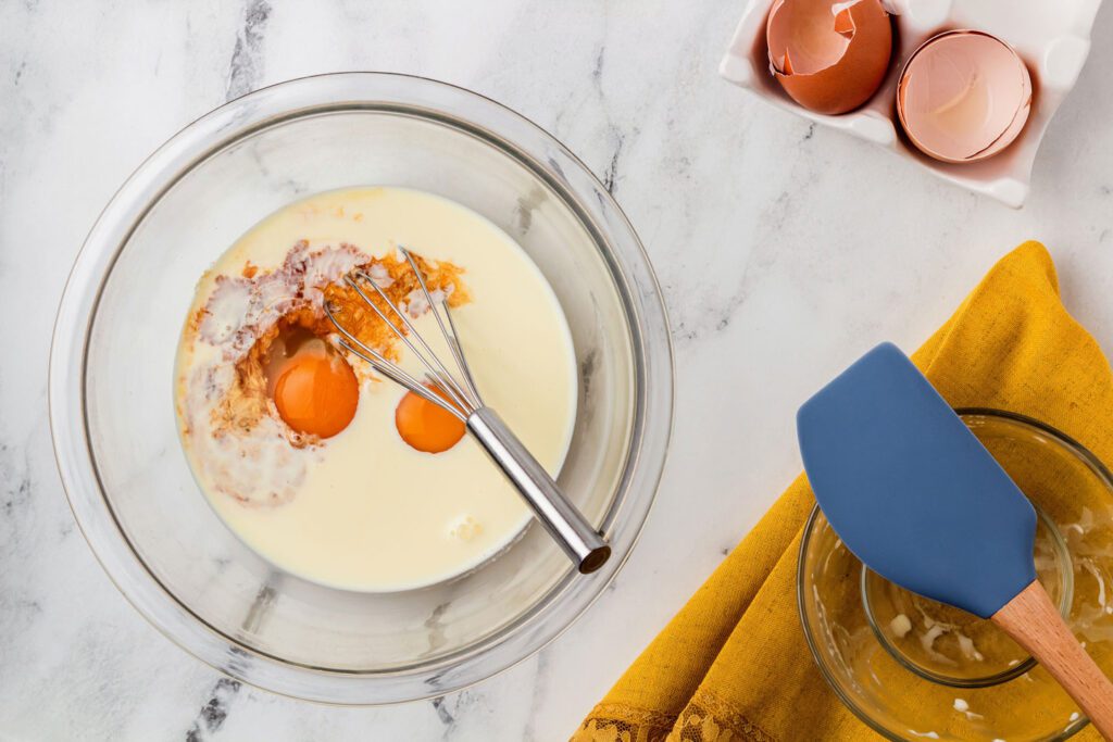 Eggs, cream, and vanilla in a bowl with a whisk