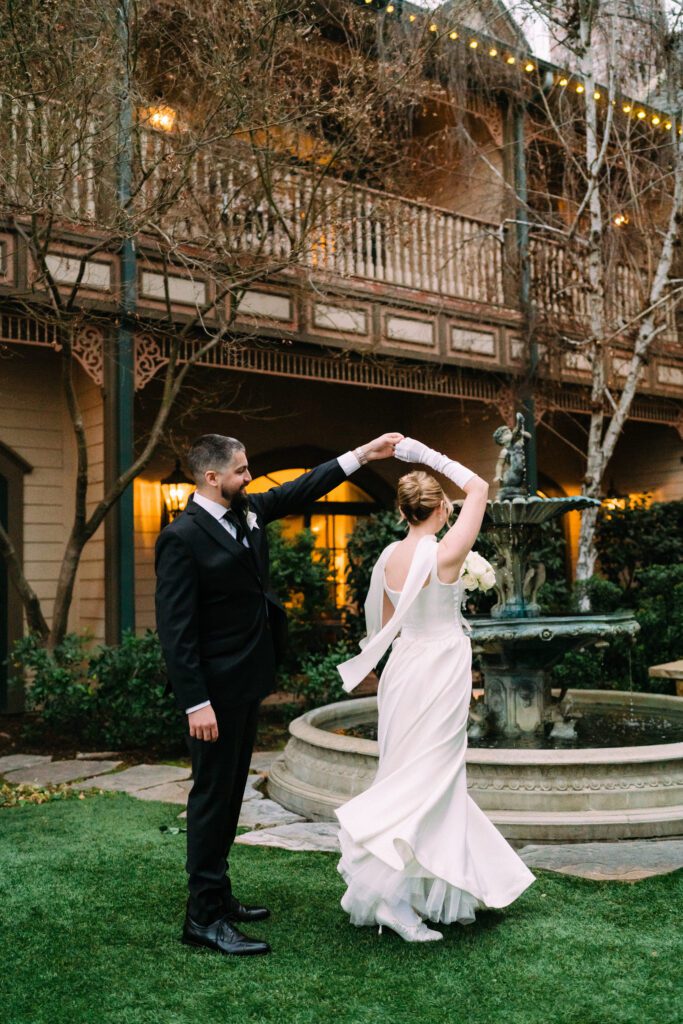 A bride and groom dancing beside an outdoor fountain at The Genevieve