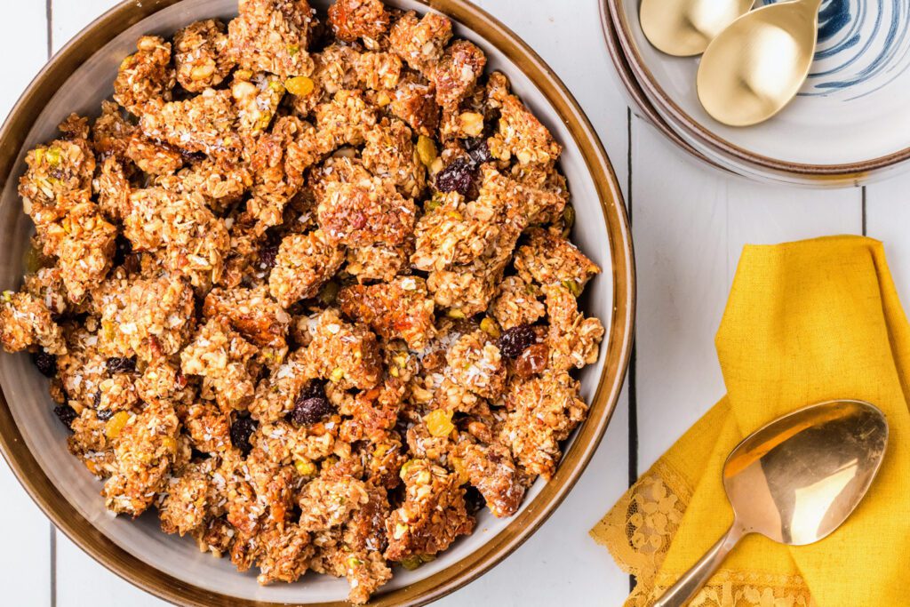 Stirring the dried fruit and the rest of the coconut into the baked oat and nut mixture.