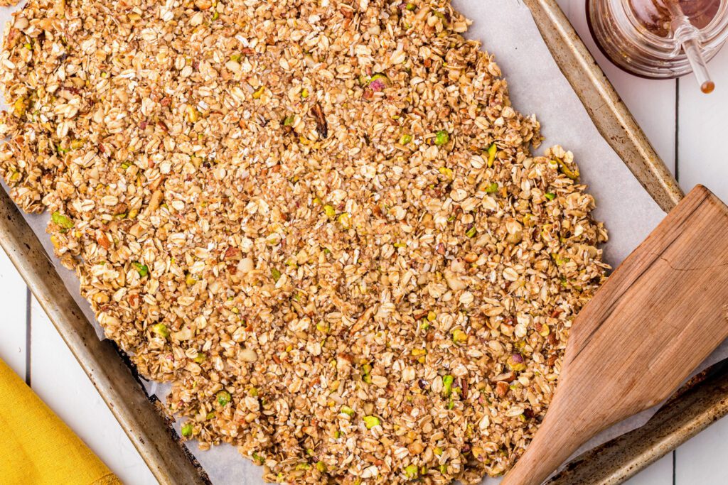 Spreading the granola onto a cookie sheet.