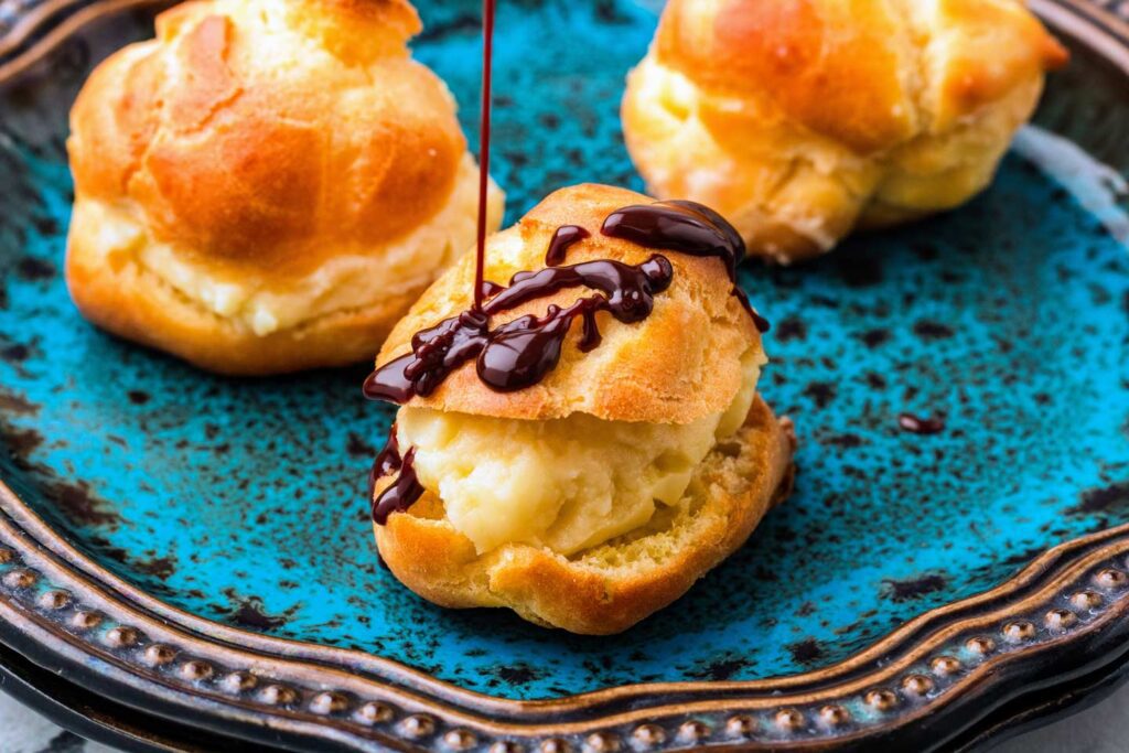 Drizzling warm chocolate sauce onto a profiterole