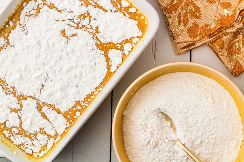 Spreading the cake mix and butter mixture evenly over the pumpkin mixture
