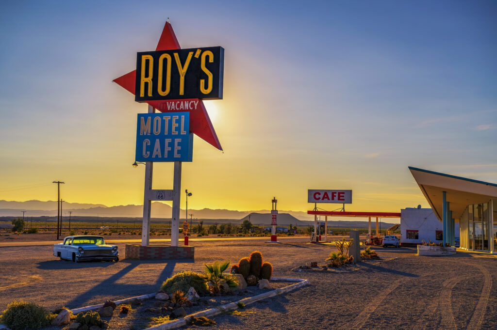 Vintage neon sign of Roy's motel and cafe on historic Route 66 in the Mojave desert, with vintage car.