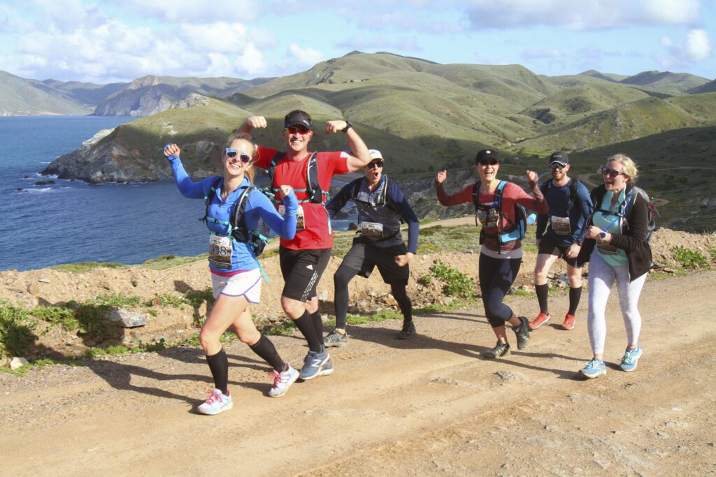 Runners on the trail of the Catalina Island Marathon with the ocean and mountainous terrain in the background