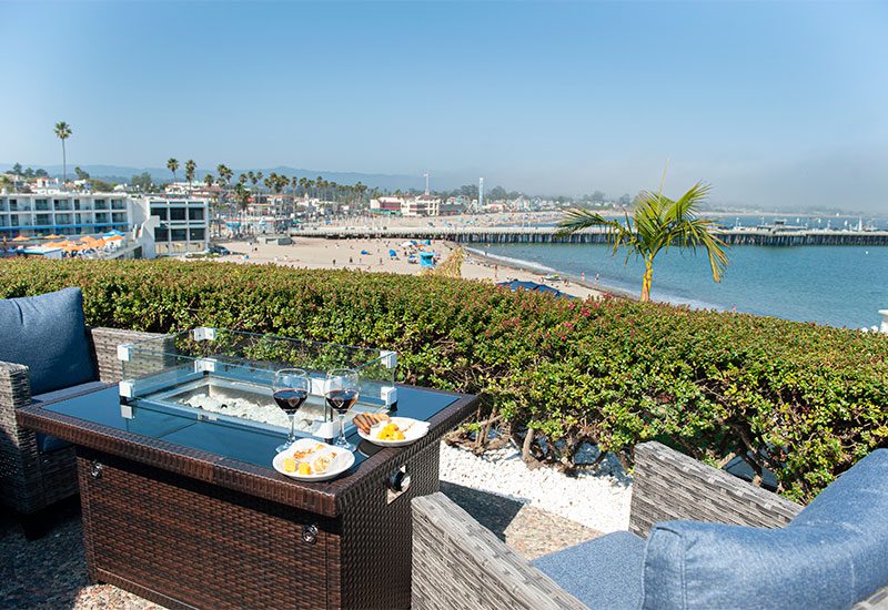 Patio seating and a fire pit overlooking Cowell's Beach, the Santa Cruz Wharf, and the Beach Boardwalk.