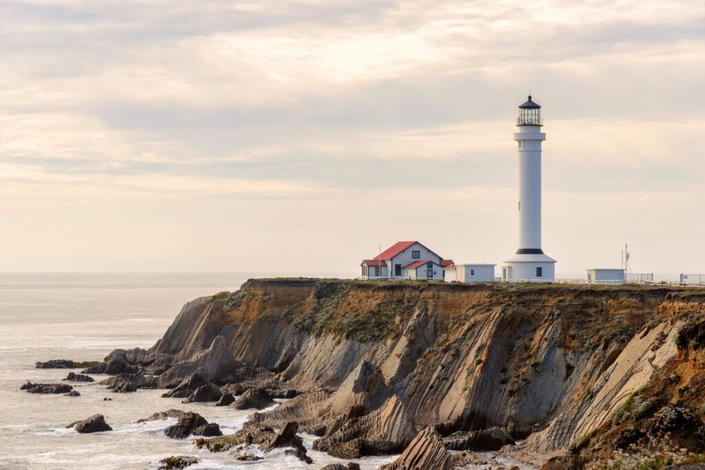 A 115-foot-tall historic  lighthouse with a keeper's house on a rocky headland