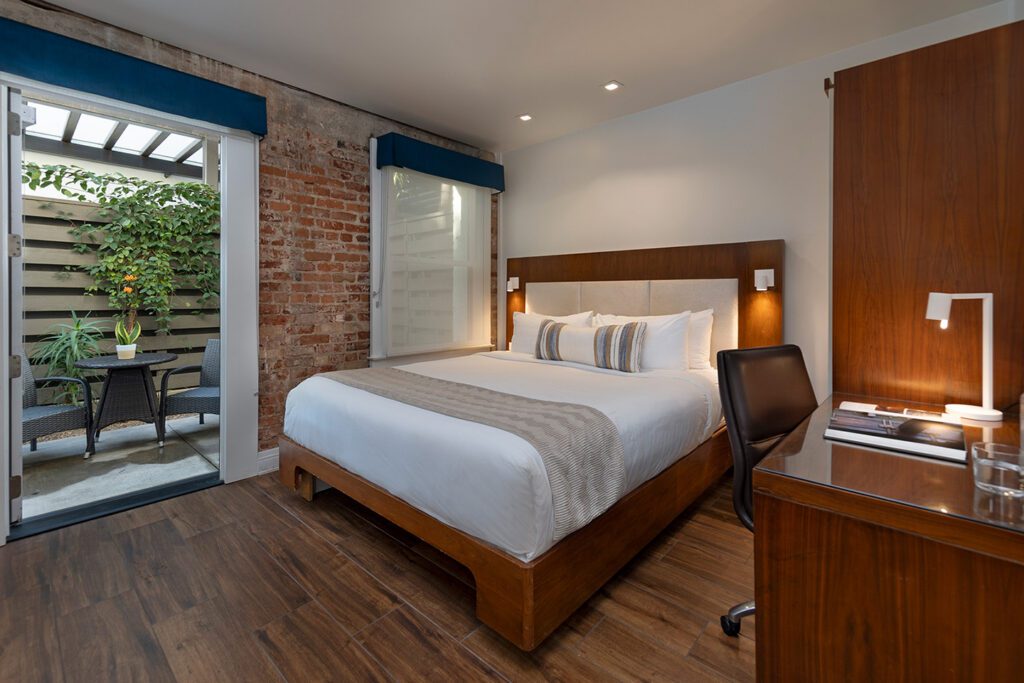 a modern hotel guest room with doors opening to a garden patio