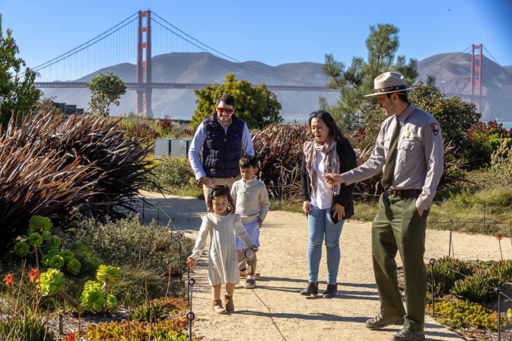 A family and a park ranger on a trail with Golden Gate Bridge in the background