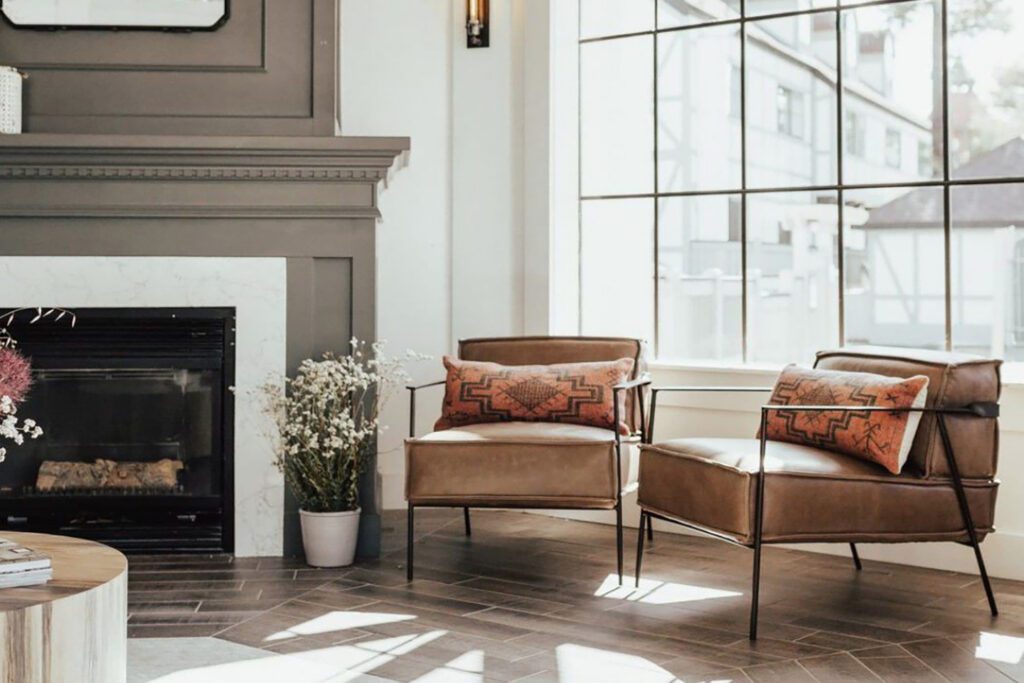 Light-filled hotel lobby with a fireplace and leather chairs with Nordic-inspired pillows
