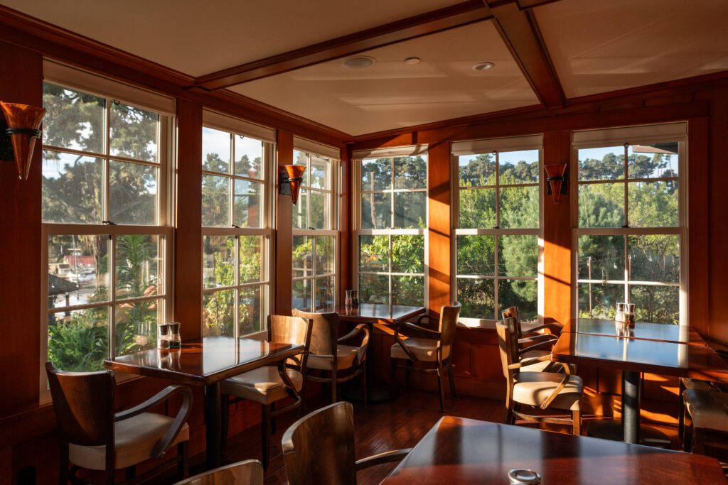 Dining room with rich wood paneling and large windows overlooking lush grounds