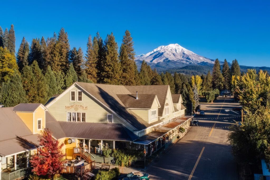 Aerial of historic McCloud surrounded by forests with Mt. Shasta's snow-capped peak rising in the background