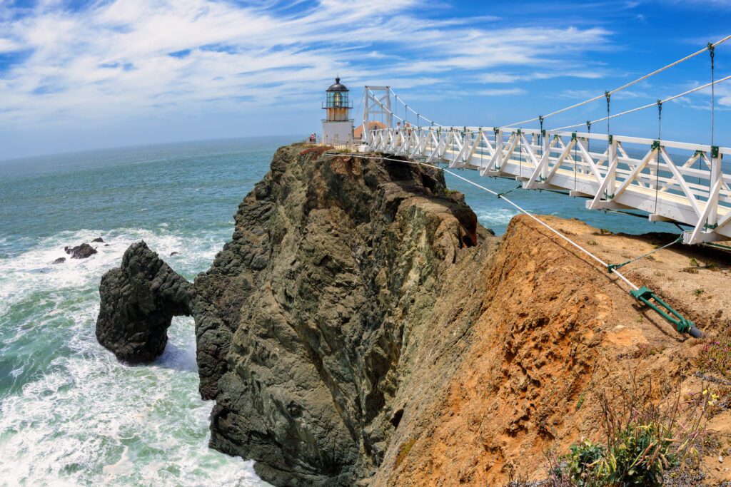 A suspension bridge leads out to Point Bonita Lighthouse perched on a rocky cliff above the ocean